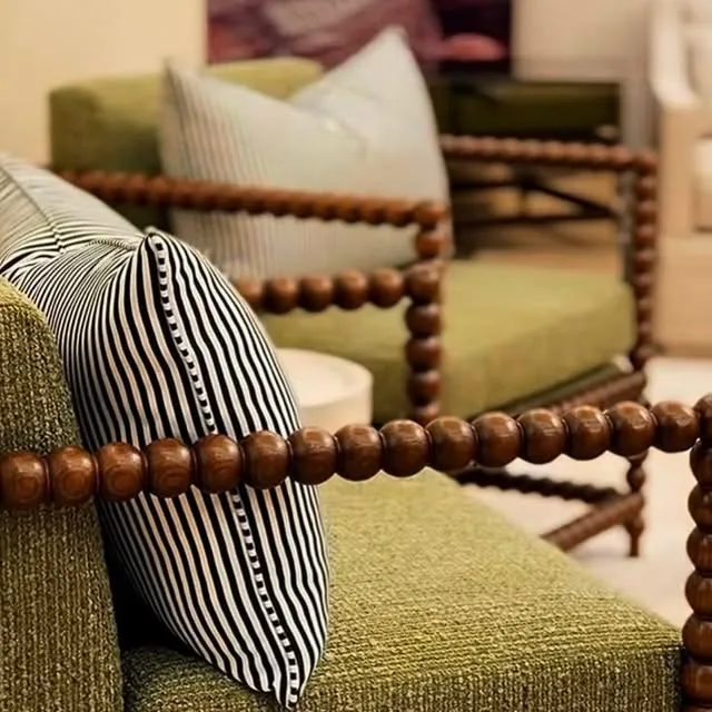 A green sofa with a striped cushion and a bobbin wood frame.