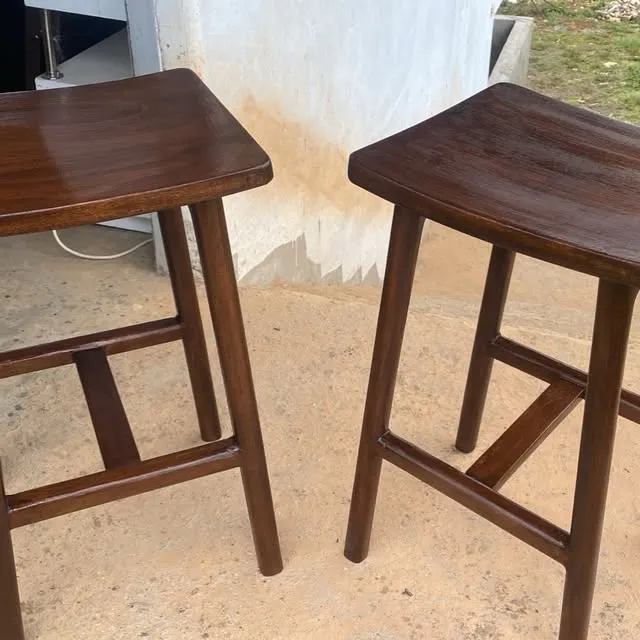 Two dark wood stools standing on a concrete floor.